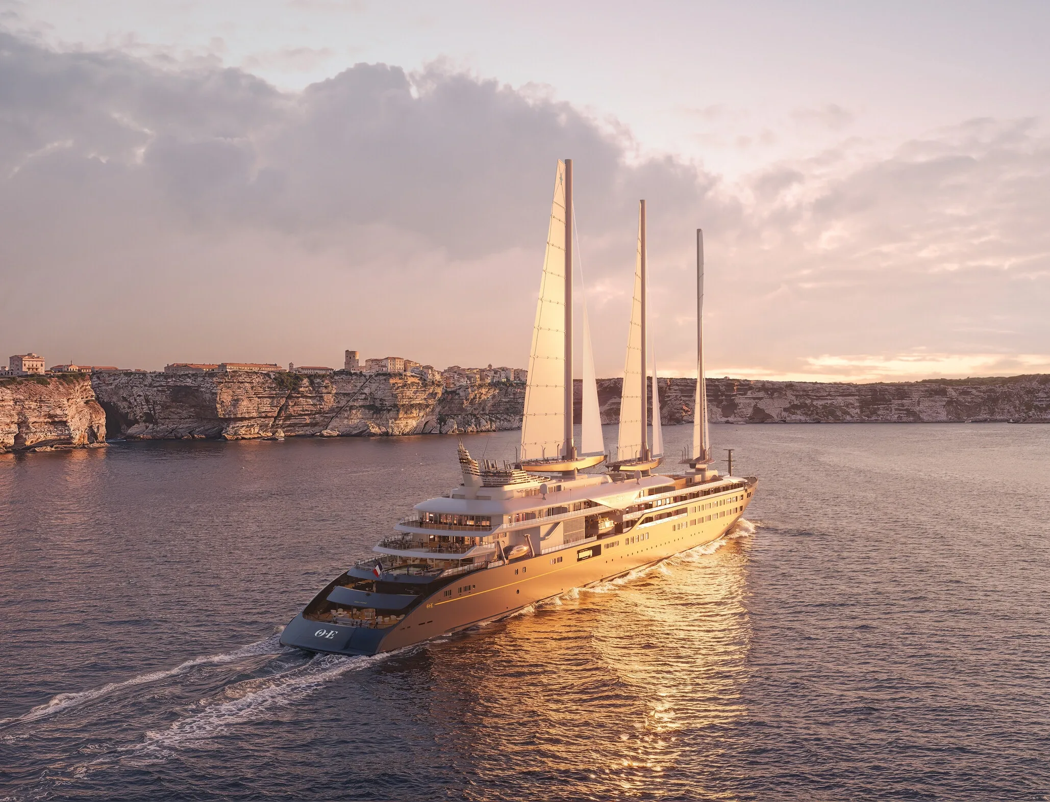 Yacht trois-mâts Corinthian glissant devant les falaises calcaires de Bonifacio au coucher du soleil