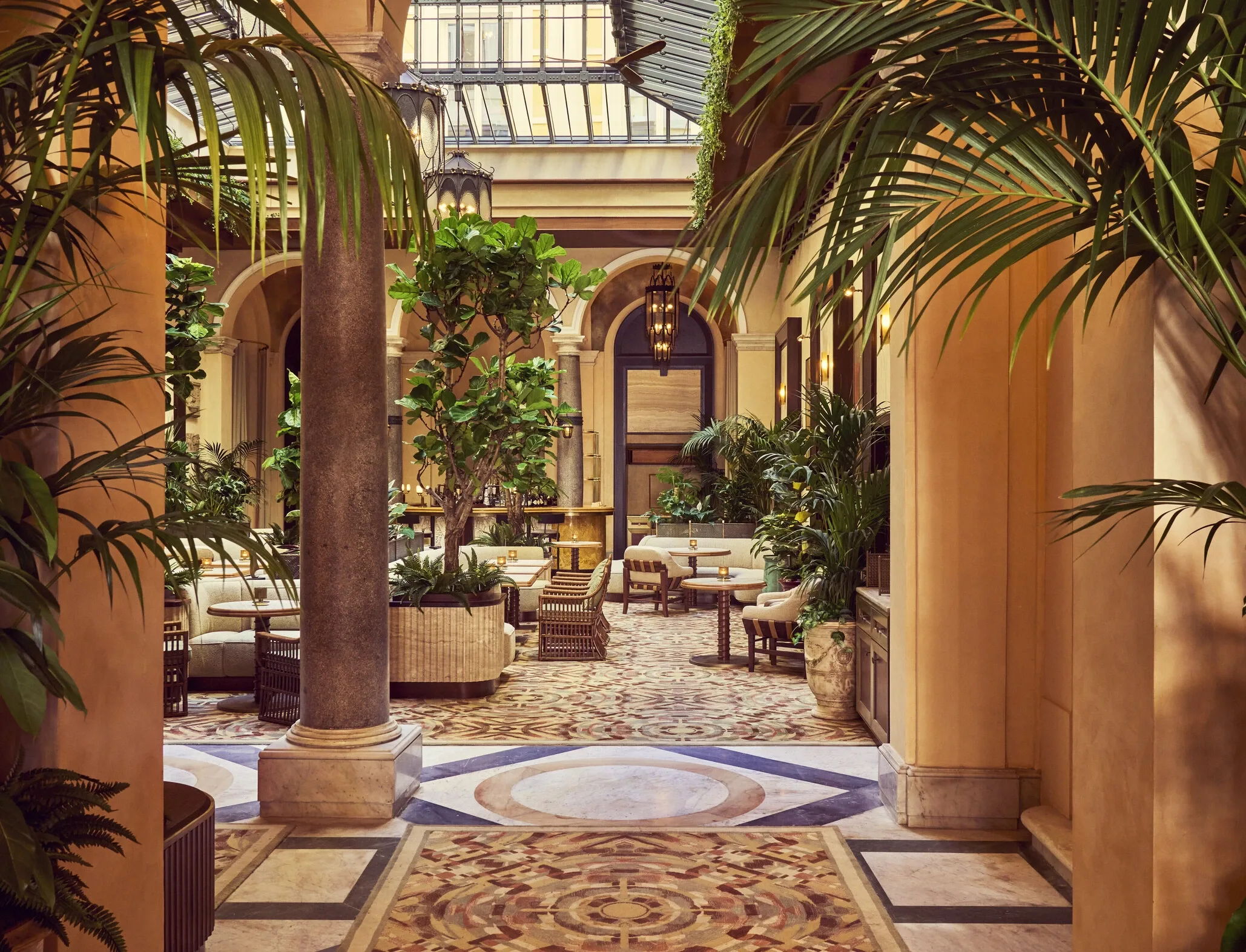 Entrée de l'hôtel Orient Express présentant une colonne en marbre et un atrium planté sous une verrière