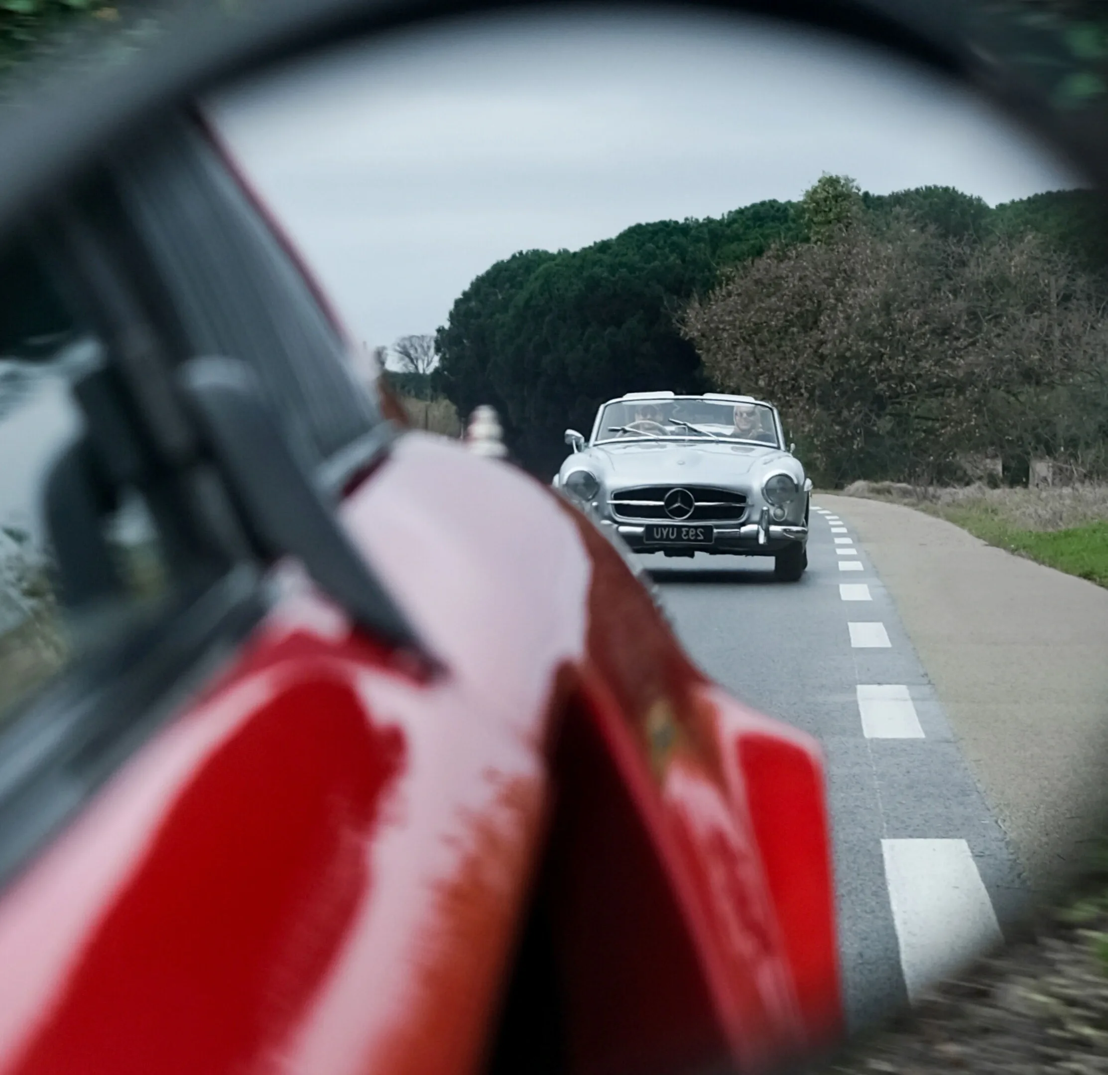 Rallye de Saint-Tropez: Mercedes 300SL décapotable suit une voiture rouge sur une route de campagne